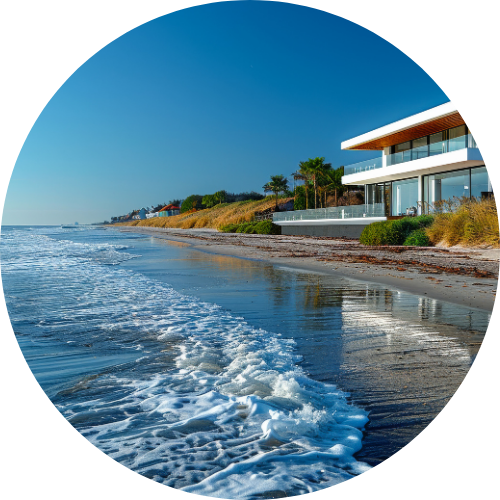 Beachfront house with green plants, sandy shore, gentle waves, and clear sky, giving a calm and fancy feel.